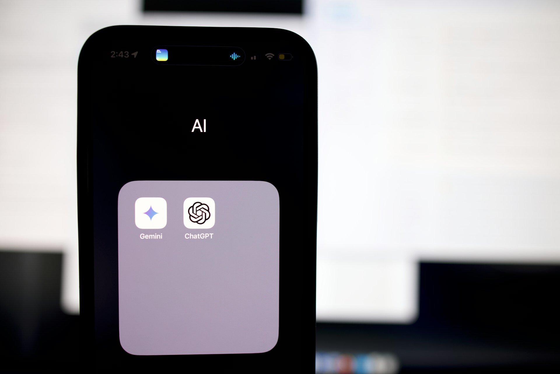 AI folder on a smartphone screen showing ChatGPT and Gemini app icons, captured in a well-lit environment