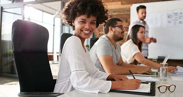 Woman smiling in office conference room holding a pen 