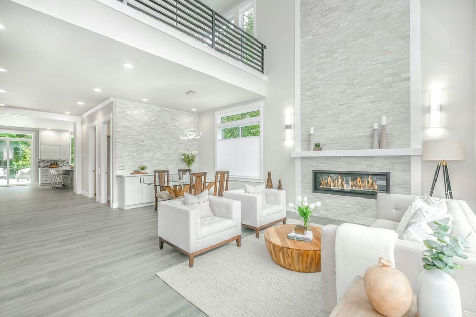 Bright living room featuring a floor-to-ceiling stone fireplace, cozy neutral furniture, and wood accents for modern home design inspiration