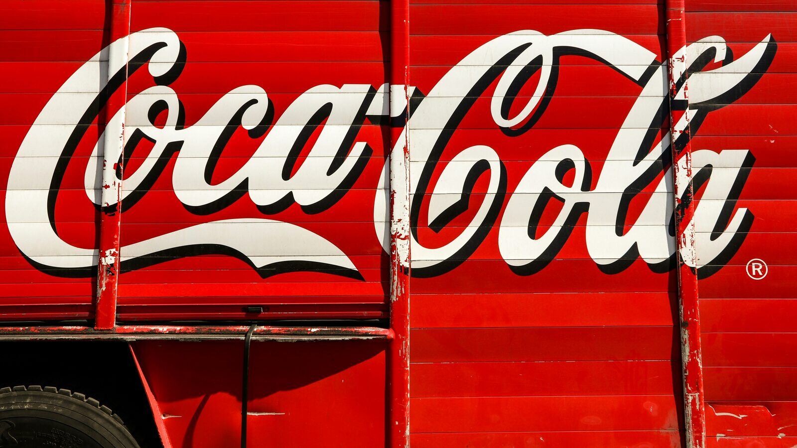 Close-up of a vintage Coca-Cola logo painted on a red delivery truck, showcasing classic branding