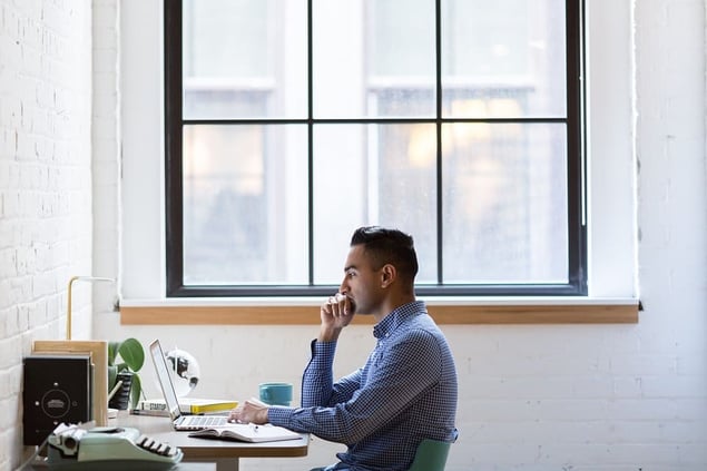 Man scrolling on laptop in an office reading negative reviews