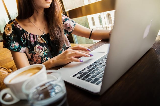 Woman sitting in coffee shop reading negative reviews on laptop