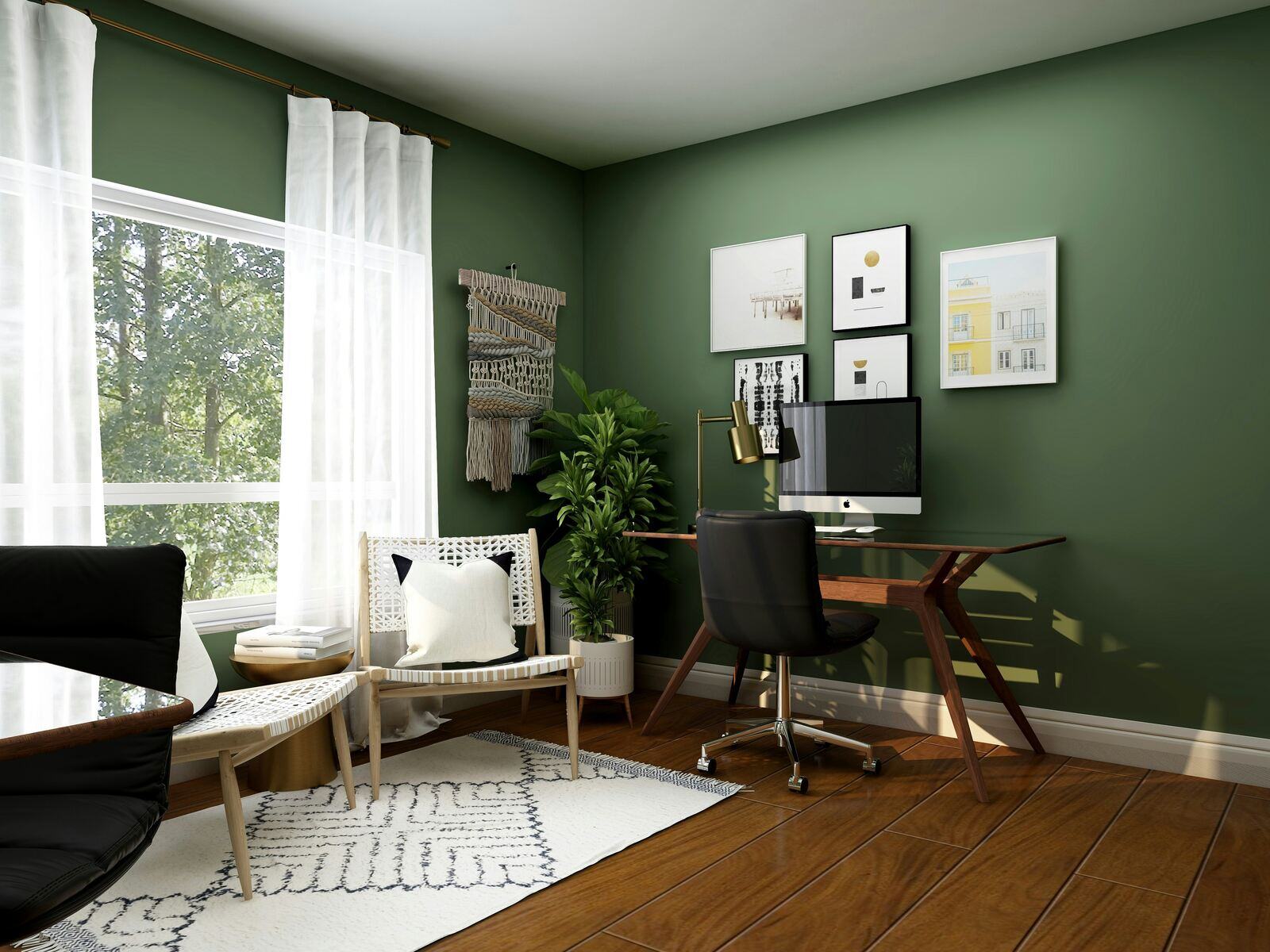 Home office with dark green walls, wooden desk, modern black chair, and gallery wall art reflecting trendy and functional workspace designs