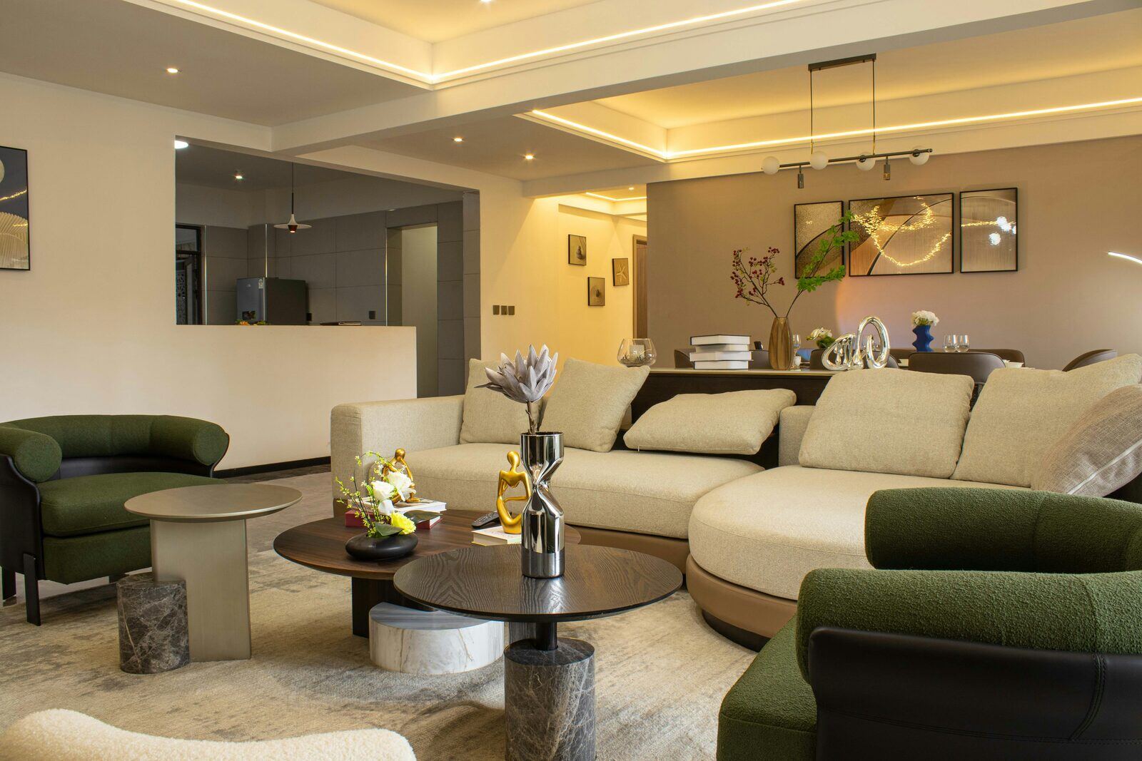 Luxury living room with modern curved beige sofa, green armchairs, and warm LED ceiling lights highlighting upscale interior design trends