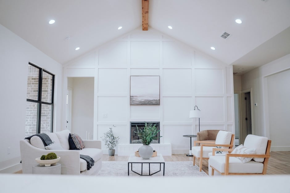 Minimalist white living room with wood beam ceiling, fireplace, and neutral-toned furniture showcasing contemporary home design trends