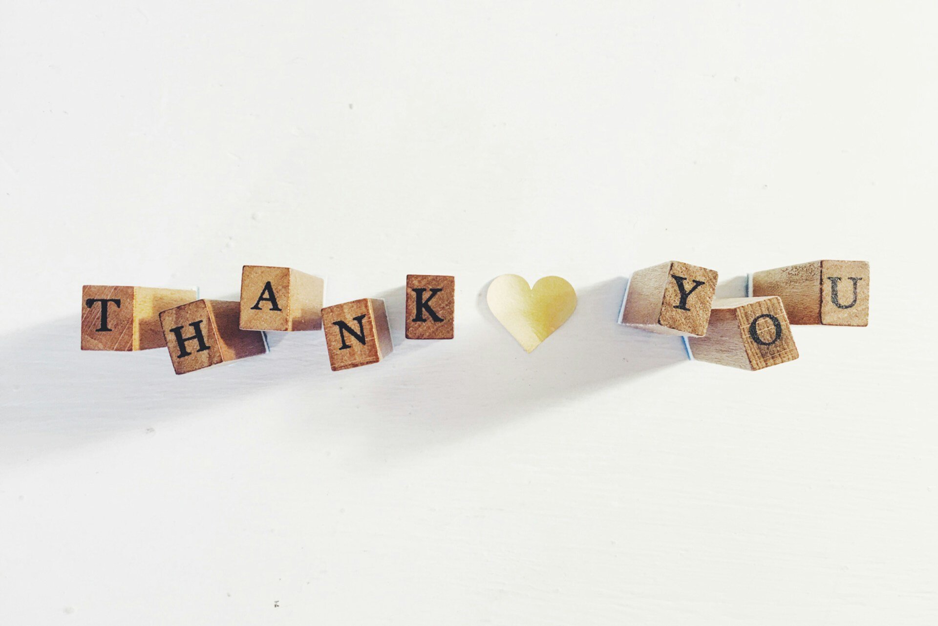 Wooden letter blocks spelling Thank You with a golden heart in the center, symbolizing thoughtful gestures and appreciation in creating exceptional client experiences for remodeling projects