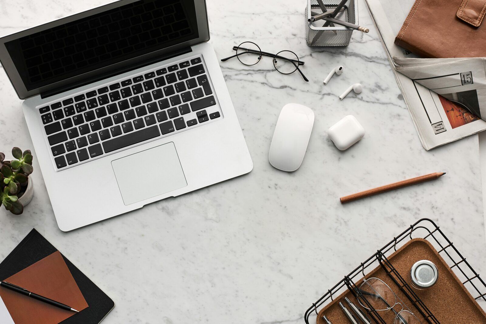 flat-lay view of a marble desk featuring a laptop, mouse, glasses, and notebook, representing professional digital strategy planning for builders. Builder Funnel.jpg