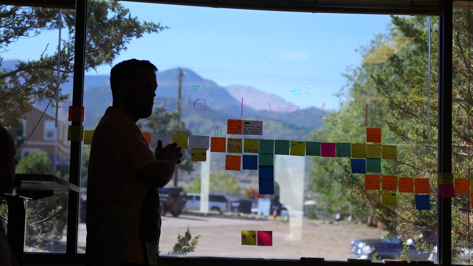 person standing in front of window strategizing home builder and remodeler marketing plan with sticky notes on window